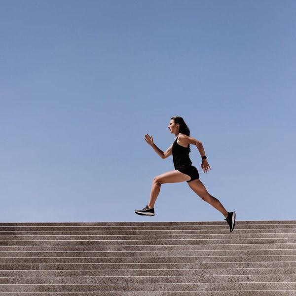 Woman performing a dynamic cardio exercise in a bright, open space.